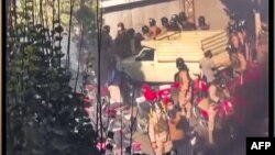 This image grab from a UGC video posted on Nov. 1, 2022, reportedly shows security forces trying to enter a closed shopping center on Amir Kabir street in Iran's capital Tehran before being engulfed by gas matter. 