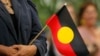 FILE - A woman holds an Aboriginal flag, Feb. 13, 2008. 