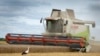 A stork walks in front of a harvester in a wheat field in the village of Zghurivka, Ukraine, Tuesday, Aug. 9, 2022