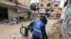 Seorang pria yang menggunakan jaket dengan logo UNRWA mengumpulkan sampah di jalanan Kota Jenin, Tepi Barat, pada 30 Januari 2024. (Foto: AFP/Jaafar Ashtiyeh)