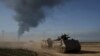 FILE - Tentara Israel bergerak dengan kendaraan pengangkut personel lapis baja (APC) di dekat perbatasan Israel-Gaza, saat asap membubung ke langit di Jalur Gaza, terlihat dari Israel selatan pada 21 Januari 2024. (AP/Leo Correa)