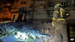 Vatrogasac istražuje oštećenja na stambenim zgradama nastala u napadu ruskim dronom na Dnjepar, Ukrajina, 23. februara 2024.