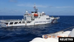 2024年2月8日,菲律宾南中国海斯卡伯勒浅滩附近,一艘中国海岸警卫队船只在菲律宾海岸警卫队船只特雷莎·马格巴努亚号附近演习.