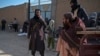 FILE - A Taliban security guard watches as food is distributed to Afghan people by the World Food Program at Nawabad Kako Sahib area in Baraki Barak district of Logar Province, Afghanistan, on Jan. 7, 2024.
