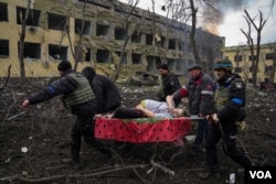 Fotografija prikazuje scenu iz filma "20 dana u Marijupolju" u kojoj ukrajinski vojnici evakuišu trudnicu iz porodilišta posle udara ruske vojske (AP)