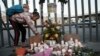 Seorang anak perempua menyalakan lilin untuk mengenang para korban kebakaran di pusat penahanan imigrasi yang menewaskan puluhan orang di Ciudad Juarez, Meksiko, Selasa, 28 Maret 2023. (AP/Christian Chavez)