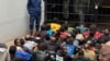 Arrested opposition members are told to sit on a cold floor surrounded by police guards at the Harare Magistrates Court in Zimbabwe, June 18, 2024.