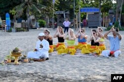 Sejumlah turis mancanegara mengikuti upacara ritual Hindu di pantai di kawasan Seminyak, Bali, 5 Agustus 2023. (Foto: Sonny Tumbelaka/AFP)