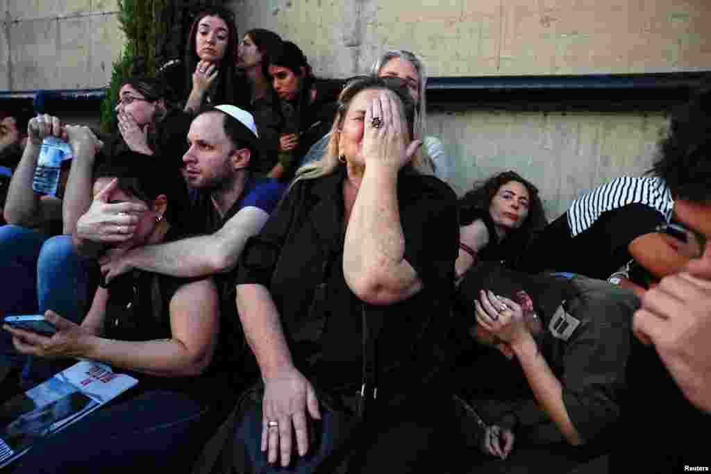 Friends and family take cover as rocket sirens sound during the funeral of Sagiv Ben Zvi, 24, who was killed following the deadly infiltration by Hamas gunmen from the Gaza Strip, in Holon, Israel, Oct. 26, 2023.