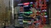 A pedestrian and office buildings are reflected on a brokerage house's window as an electronic board displaying Shanghai shares trading index in Beijing, Feb. 5, 2024. 