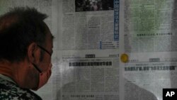 FILE - A man reads a Global Times article on investment curbs aimed at China, in Beijing, Aug. 10, 2023. China has accused Washington of trying to block its development via investment restrictions.