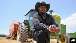 FILE - Farmer John Boyd Jr., poses for a portrait during a break from baling hay at his farm in Boydton, Va., May 27, 2021. 