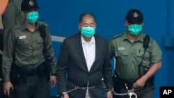 FILE - Jimmy Lai is escorted by Correctional Services officers to get on a prison van before appearing in a court in Hong Kong, Dec. 12, 2020.