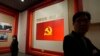 FILE - Visitors stand near a flag of the Chinese Communist Party at an exhibition in Shanghai, April 20, 2023. Foreign investment in China fell for the 12th consecutive month in May, according to China’s Ministry of Commerce.   