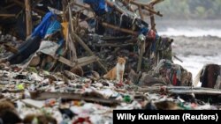 Seekor kucing terlihat di antara sampah yang sebagian besar berupa sampah plastik dan rumah tangga, di sebuah pantai di perkampungan nelayan Teluk, Pandeglang, Banten, 15 Maret 2024. (Foto: REUTERS /Willy Kurniawan)