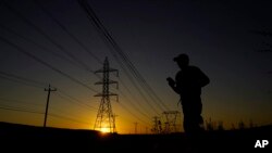 A jogger passes under power lines during an evening run, June 26, 2023, in San Antonio. Meteorologists say scorching temperatures brought on by a heat dome threaten to bring record highs to the state.
