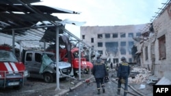 烏克蘭救援人員走過烏東城市第聶伯河（Dnipro）一座被摧毀的救火站，救火站裡停著幾輛燒毀的緊急救援車輛。照片時間是2023年5月22號。