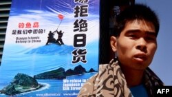 一名男子走過北京秀水街頭一幅「拒絕日貨」的宣傳牌。 （2012年9月17日）