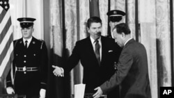 1984年1月12日，時任美國總統裡根在白宮西廳向時任中國總理趙紫陽示意在簽署美中科技協議之前就座。（美聯社照片）
