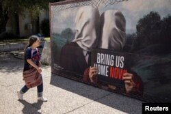 Seorang wanita berjalan di samping sebuah poster solidaritas untuk membebaskan para sandera yang diculik selama serangan ke Israel pada 7 Oktober 2023 oleh kelompok militan Palestina Hamas dari Gaza, di kota Tel Aviv, Israel, 31 Mei 2024.