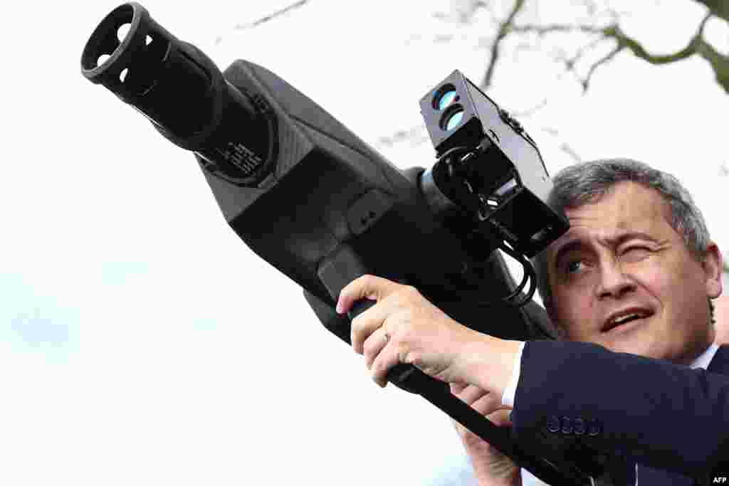 France's Minister for Interior and Overseas Gerald Darmanin holds an anti-drone weapon during the Olympic flame's journey, in Beynes, west of Paris.