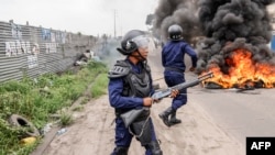 Democratic Republic of Congo police officers stand next to a burning barricade during an opposition demonstration in Kinshasa, Dec. 27, 2023. Police were deployed in the capital Kinshasa during a banned demonstration against recent elections.