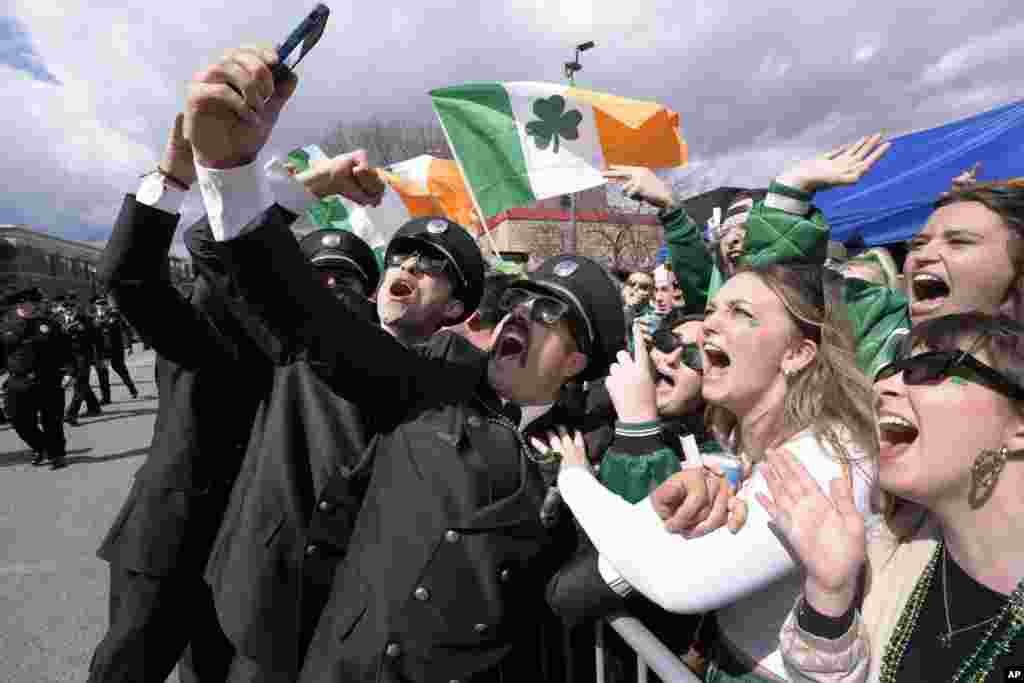 A group of firemen from around the United States pose for a selfie with spectators while marching in the St. Patrick's Day parade, March 17, 2024, in South Boston neighborhood, Massachusetts.