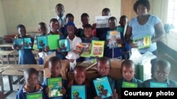 Vana vepachikoro cheDekezi Primary School nemukuru wechikoro vachiratidza mabhuku akabva kusangano reZimbabwe Rural Schools Library Trust.