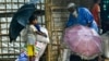 FILE - Rohingya refugees wait at a food distribution place during monsoon rainfall in Kutupalong refugee camp in Ukhia, Bangladesh, August 10, 2022.