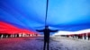 FILE - A Navy school cadet stands under a giant Russian flag during an action to mark the ninth anniversary of the Crimea annexation from Ukraine, in St. Petersburg, Russia, March 18, 2023. 