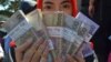 Seorang perempuan memperlihatkan uang yang akan dibagikan kepada para kerabat untuk Idul Fitri di Malang, Jawa Timur, 15 Juni 2016. (Foto: Aman Rochman/AFP/ilustrasi)