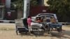 Três homens deitados em carrinhos de madeira numa rua de Luanda, a 3 de julho de 2015