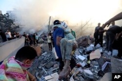 A Palestinian man evacuates a wounded girl out of the destruction following Israeli airstrikes on Gaza City, Oct. 25, 2023.