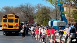 Children from The Covenant School hold hands as they are taken to a reunification site at the Woodmont Baptist Church after a deadly shooting at their school, in Nashville, Tennessee, March 27, 2023.