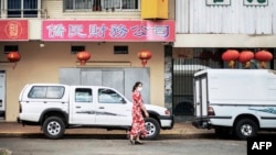 FILE - A woman walks in Cyrildene, also known as Johannesburg's Chinatown, South Africa, Feb. 7, 2020.