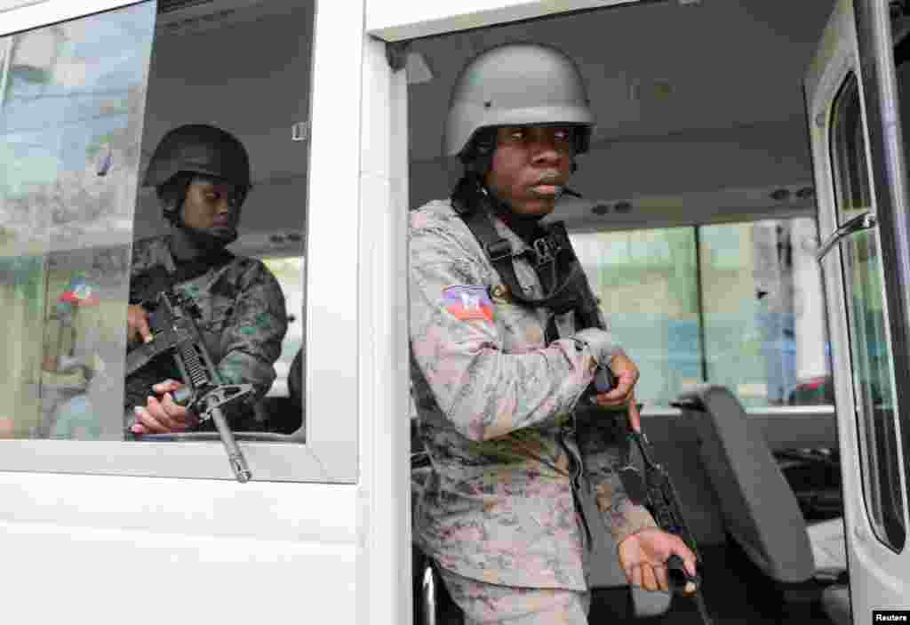 Polisye PNH kanpe nan yon machin lapolis devan bilding kote yo pral nomen Michel Patrick Boisvert nouvo Premye Minis enterime Ayiti nan Potoprens, 25 Avril, 2024.