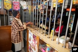 Linnah Mueni, left, buys a bag of maize flour from a small shop in Kitengela, on the outskirts of the capital Nairobi, Kenya, April 17, 2023.