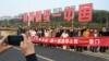 中國福建廈門豎立起一個台灣金門島可以看到的“一國兩制統一中國”的大型標語牌，旅遊者在前拍照。 （2024年1月12日）
