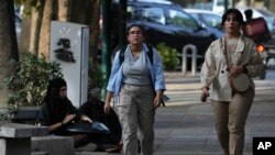 FILE - Iranian women walk in Tehran, Iran, neither wearing a hijab, on Aug. 5, 2023. Iran's parliament has passed legislation that imposes severe penalties for hijab violations. The law is to take effect Dec. 13, 2024.
