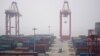 FILE - Trucks move past containers at the Yangshan Deep Water Port in Shanghai, China, Jan. 13, 2022.