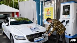 Seorang petugas sedang mengisi daya mobil listrik dalam perhelatan G20 di Nusa Dua, Bali, 25 Maret 2022. (Foto: Sonny Tumbelaka/AFP)