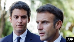 FILE - French Education and Youth Minister Gabriel Attal (L) looks at France's President Emmanuel Macron addressing the audience at a vocational school in Orange, Southeastern France, Sept. 1, 2023.
