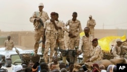 FILE - Sudanese soldiers from the Rapid Support Forces stand on their vehicle during a military-backed rally in Mayo district, Sudan, on June 29, 2019. 