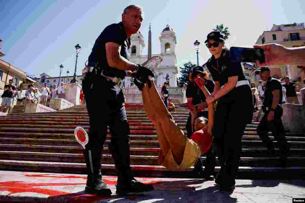''Bruciamo tutto'' (Let's burn everything) activist is removed by police after she poured red paint on the Spanish Steps to protest against femicides in Rome, Italy.