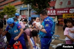 由志願者組成的中國民間救援隊藍天救援隊成員在河南鄭州對洪災災民實行救援。（2021年7月22日）