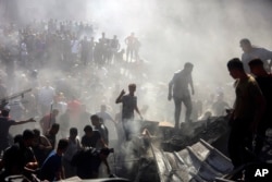 Warga Palestina memeriksa puing-puing bangunan yang hancur akibat serangan udara Israel di kota Khan Younis, Jalur Gaza selatan, Kamis, 26 Oktober 2023. (AP/Mohammed Dahman)