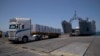 FILE - Trucks arrive loaded with humanitarian aid at the U.S.-built floating pier before reaching the beach on the coast of the Gaza Strip, June 25, 2024.