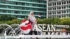 Seorang ibu berpose di dekat logo Association of Southeast Asian Nations (ASEAN), usai upacara peresmian Indonesia sebagai ketua ASEAN untuk 2023, di Jakarta, 29 Januari 2023. (Foto:Goh Chai Hin / AFP)