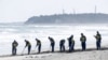 Polisi mencari petunjuk tentang orang hilang dari bencana gempa bumi dan tsunami tahun 2011 di pantai dekat PLTN Fukushima Daiichi yang lumpuh akibat tsunami di kota Namie, prefektur Fukushima, Jepang, 11 Maret 2024, pada peringatan 13 tahun bencana tersebut. (Kyodo via REUTERS)