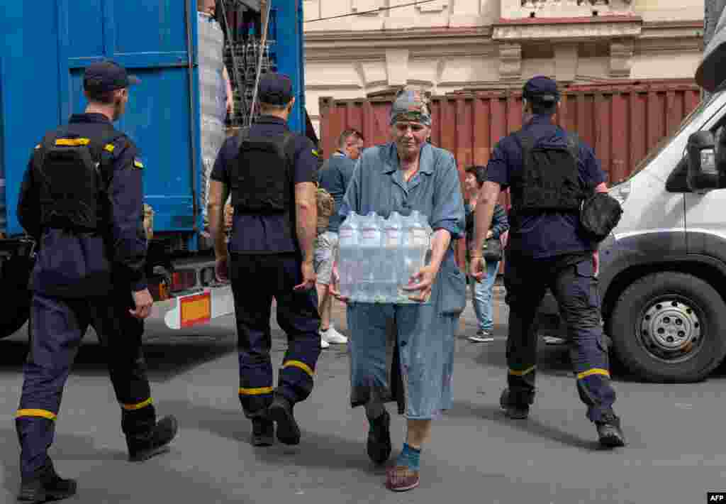 Rescuers and volunteers unload bottles of drinking water from a vehicle during an evacuation from a flooded area in Kherson, June 8, 2023, following damages sustained at Kakhovka hydroelectric power plant dam.